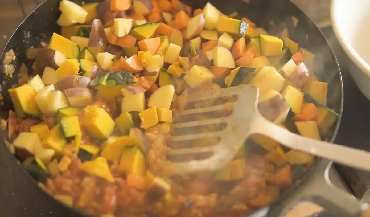 お腹をあっためるルーカレーほっこり風味 フライパンで玉ねぎ、プチトマト、にんじんなどを炒めている