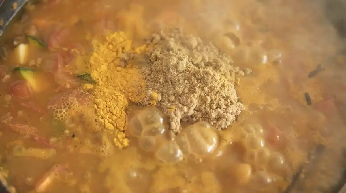 お腹をあっためるルーカレーほっこり風味 野菜を炒めたフライパンに、パウダースパイスと豆乳ヨーグルトを加えている