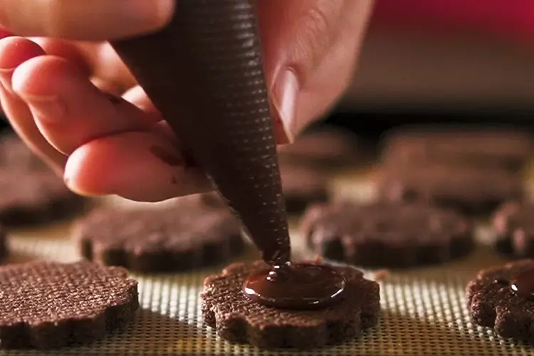チョコレートクッキーに溶かしたチョコを絞っている